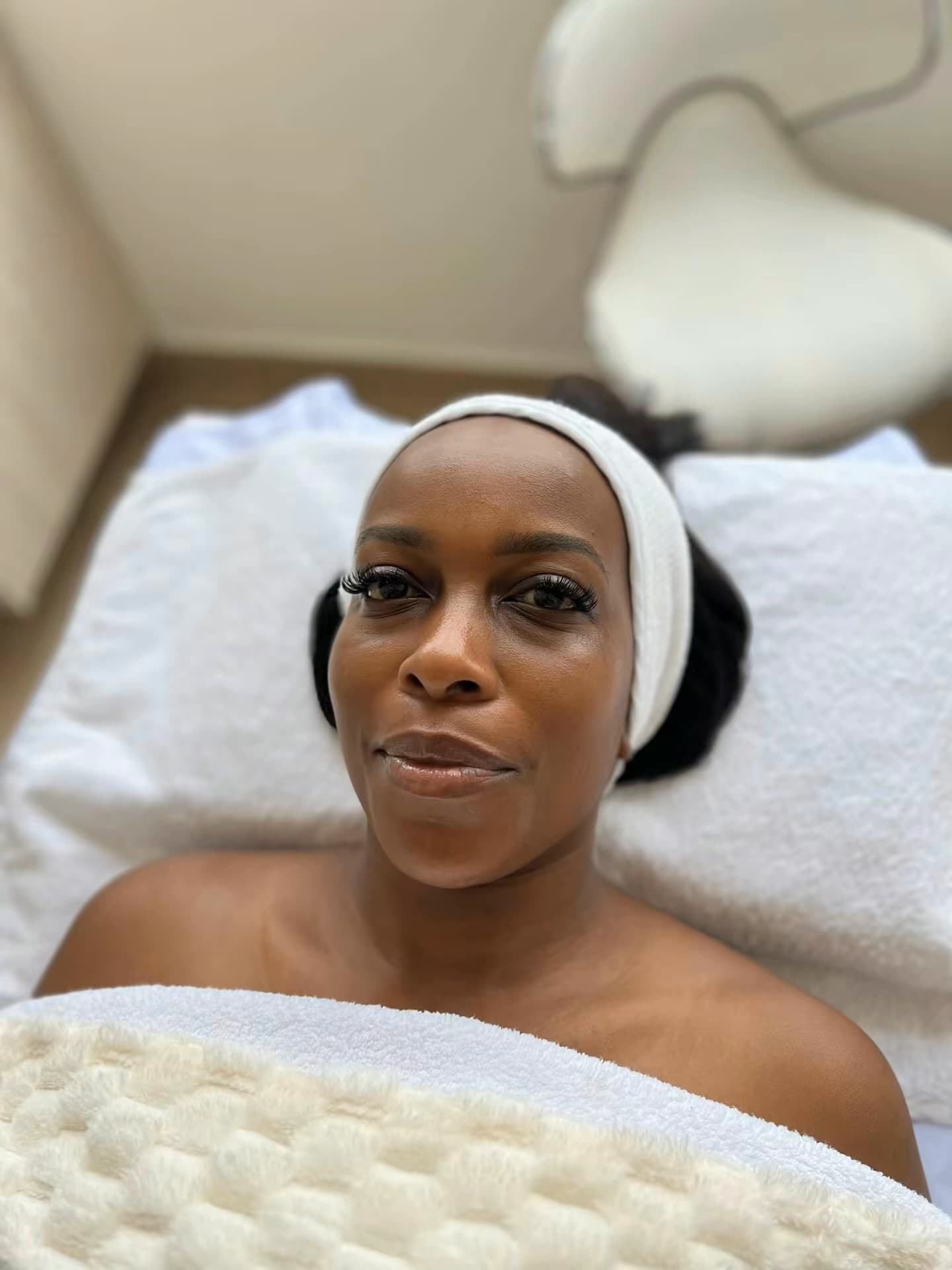 A client relaxing on the treatment bed at Skin by Lyze, wrapped in a warm towel before her corneotherapy facial