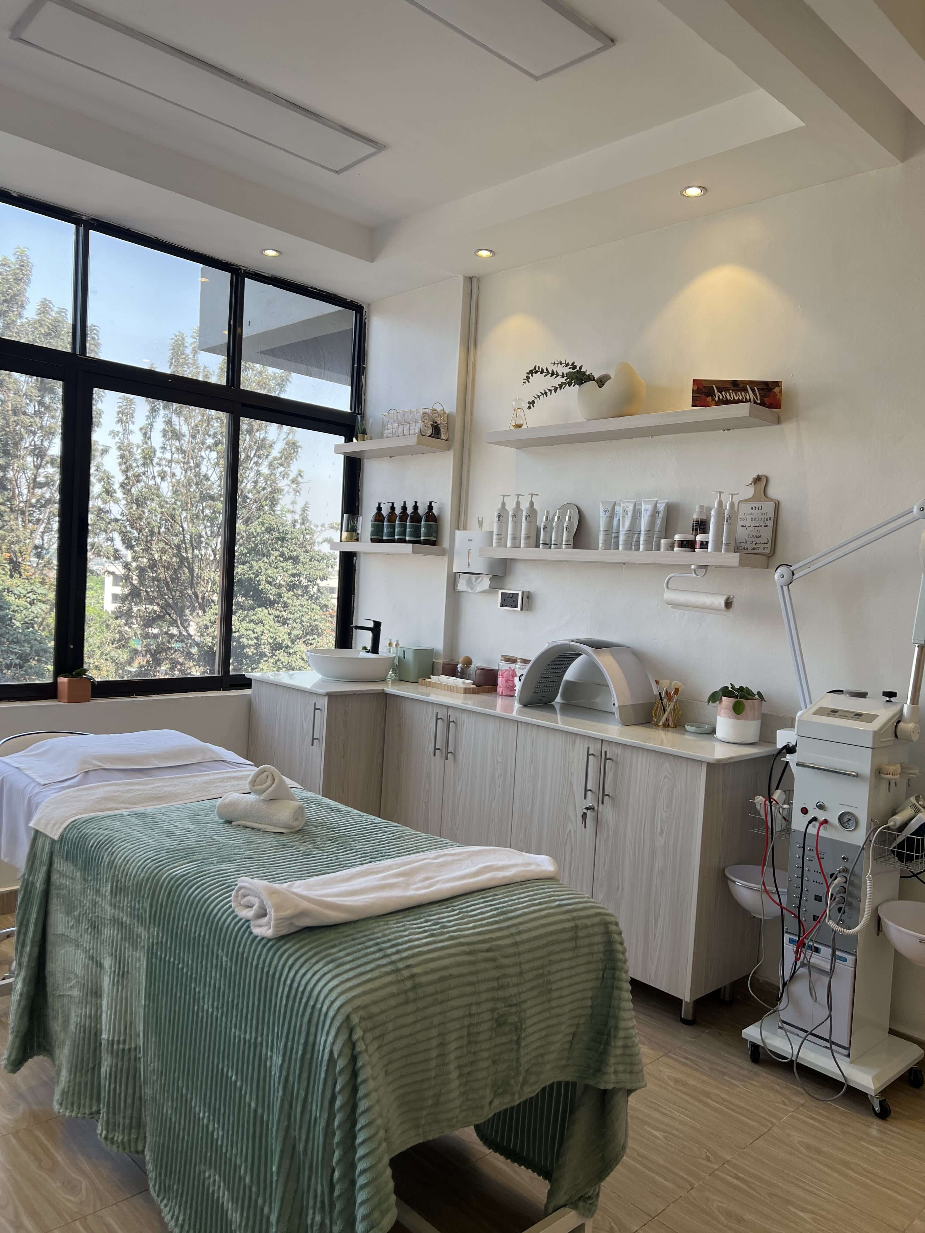 The Skin by Lyze treatment room in Nairobi, with a facial bed and skincare product shelves by a bright window