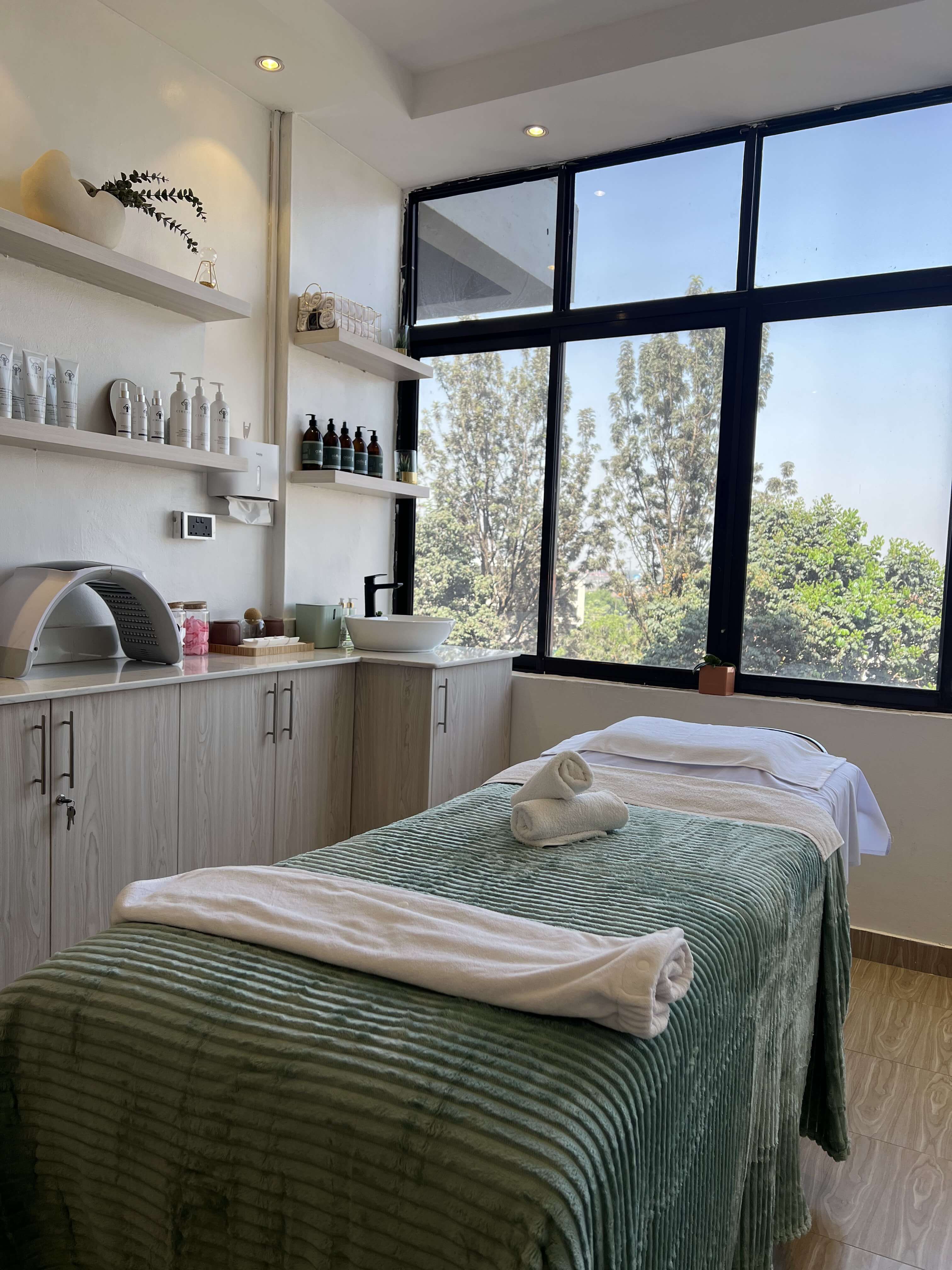 A facial treatment bed at Skin by Lyze dressed with fresh towels beside a large window